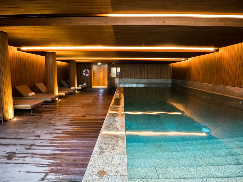 A long indoor pool in warm timber, lit low along the walls.