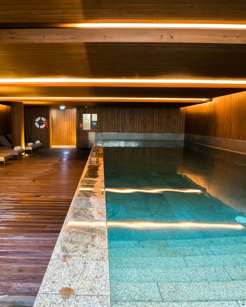 A long indoor pool in warm timber, lit low along the walls.